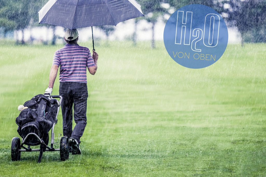 Mann geht im Regen über den Golfplatz