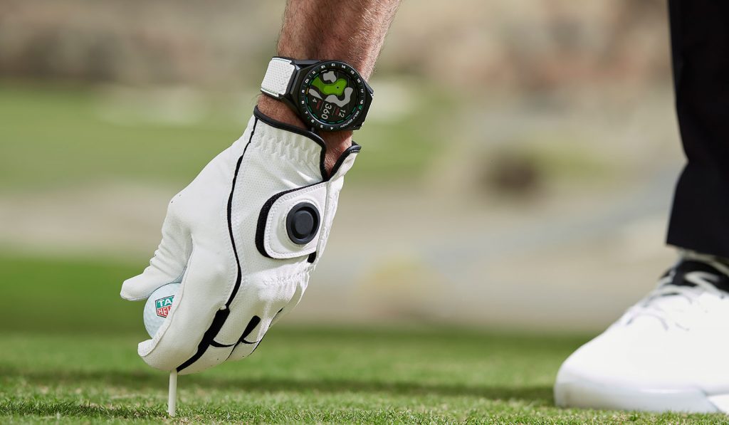 Golfer platziert Golfball auf Tee und trägt eine TAG Heuer Connected Modular 45 Golf Edition Smartwatch