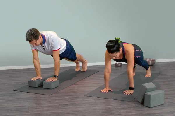 3. Beim Ausatmen legst du die Hände auf den Boden und streckst die Füße nacheinander aus, ein sogenannter Stütz. Achte darauf, dass der Rücken und Gesäß gerade, wie ein Brett sind, der Bauch ist angespannt und die Hände stehen unter den Schultern. Atme in dieser Position zweimal tief ein und aus.