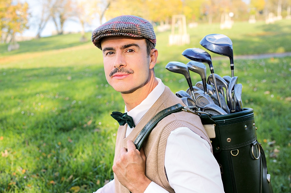 Golfer mit Tweedmütze und Golfbag auf einem Golfplatz